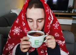 Młody chłopak pije herbatę przykryty kocem