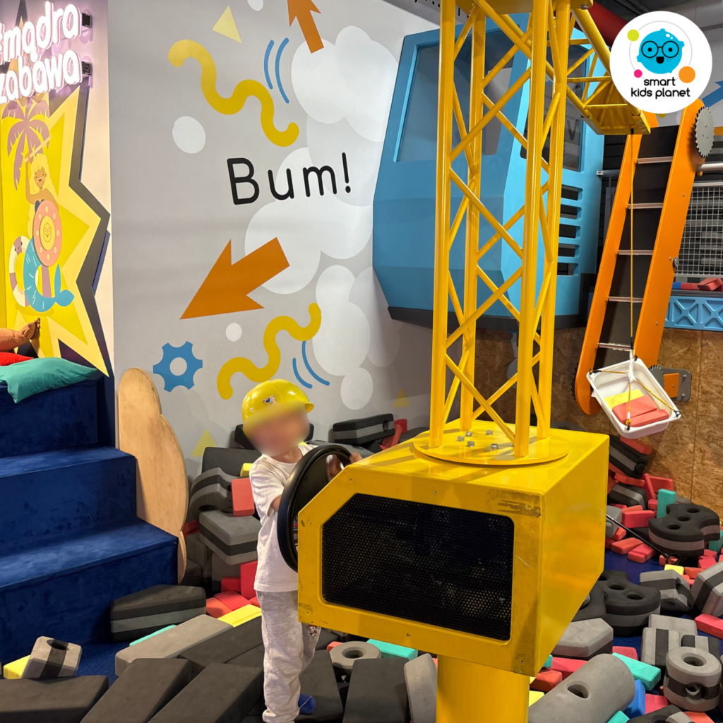 Dziecko w kasku budowlańca bawi się dużą maszyną