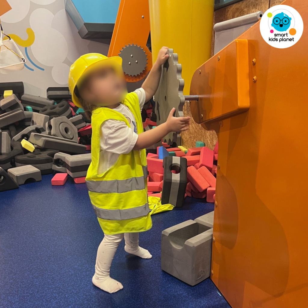 Dziecko w kasku budowlańca bawi się dużą maszyną