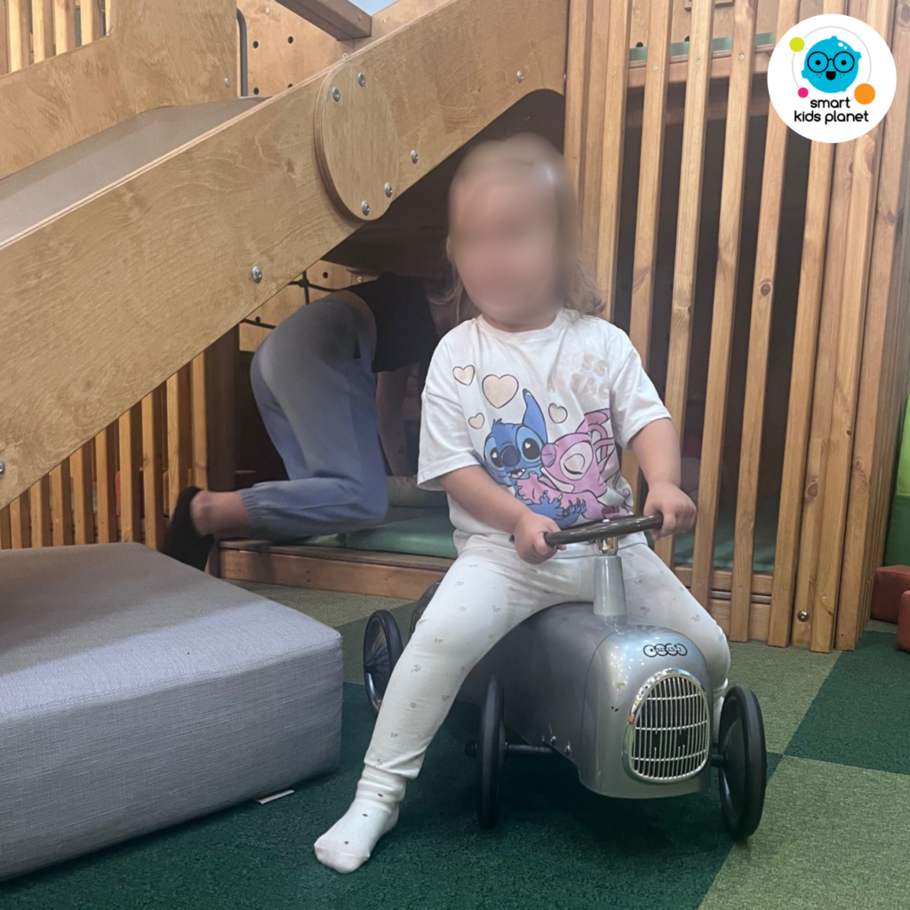 Dziewczynka siedzi na zabawkowym pojeździe